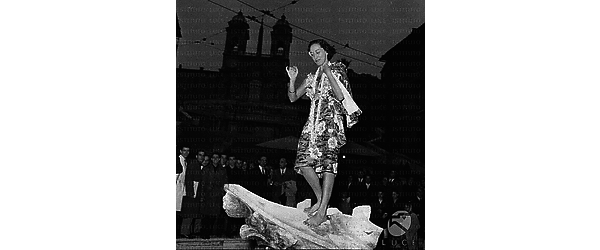 La danzatrice hawaiana Kalei O' Kuaihelani in costume tipico a piazza di Spagna in piedi sulla fontana della Barcaccia - totale