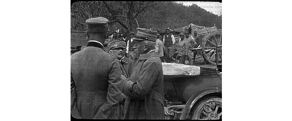 Il generale Cadorna e Vittorio Emanuele d'Aosta conte di Torino discutono con altri dello Stato Maggiore; sullo sfondo alcune carrozze e abitanti del posto