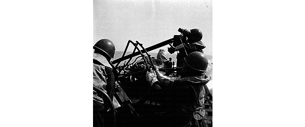 Marinai guidati da un commilitone con un binocolo puntano una mitragliatrice verso il cielo
