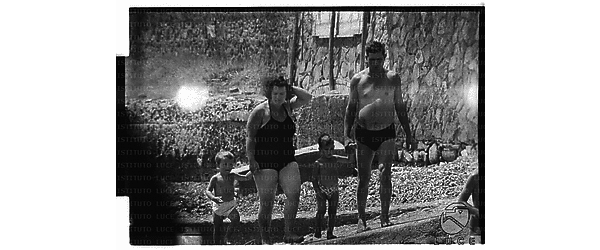 Un uomo ed una donna con due bambini per mano ripresi in piedi sugli scogli di Santa Marinella - totale