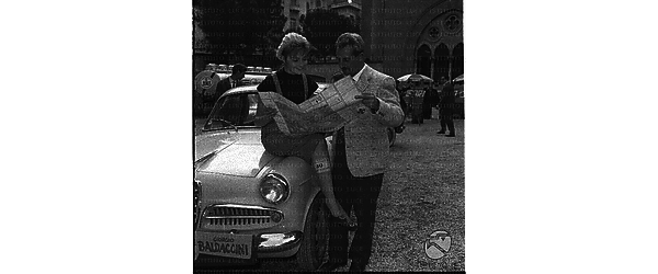 Patrizia Della Rovere seduta su una automobile osserva una piantina con Giorgio Baldaccini. Totale