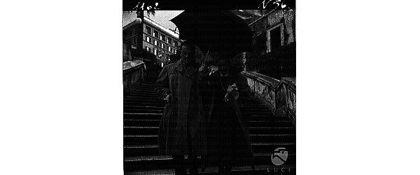 Maria Schell e Luchino Visconti scendono la scalinata di Trinità dei Monti coprendosi con l'ombrello - totale