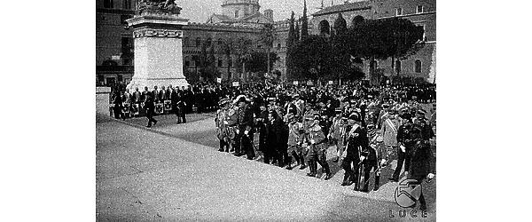 Roma Mussolini e Vittorio Emanuele III, seguiti da un gruppo di autorità militari e politiche in alta uniforme, salgono la scalinata dell'Altare della Patria