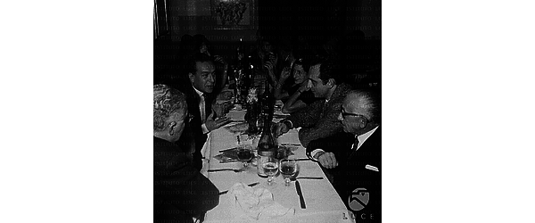 Roma Renato Guttuso, seduto a un tavolo, conversa con gli altri commensali, tra cui Michelangelo Antonioni, di fronte a lui