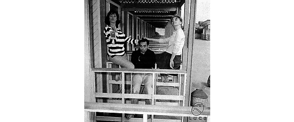 Lynn Shaw con Alessandra Panaro e Fulvio Carrara all'esterno di una cabina sulla spiaggia. Totale
