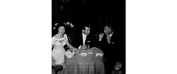 Richard Egan seduto ad un tavolino con la moglie e Raul Walsh