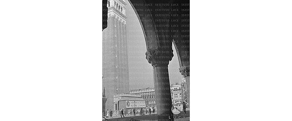 Il campanile e un tratto di Piazza San Marco con le strutture difensive anti-bombardamento, su una di queste si vede la pubblicità di un cinema con i titoli: "L'assedio dell'Alcazar" e "Oltre l'amore"