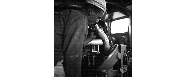 Un marinaio in cabina di comando manda un messaggio vocale sottocoperta usando un sistema di tubi