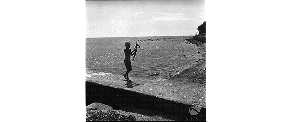 Un bambinetto ripreso sul molo della spiaggia di Santa Marinella con un arpione in mano - totale