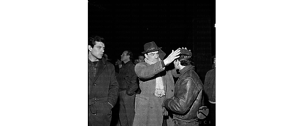 Milano Luchino Visconti, in esterni, di notte, con alcuni attori sul set del film Rocco e i suoi fratelli