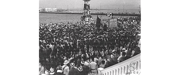 Folla festosa,con autorità militari italiane,ascari e civili esultanti lungo un molo, in occasione dell'arrivo di Umberto di Savoia in Eritrea - campo lungo. Scorcio dall'alto