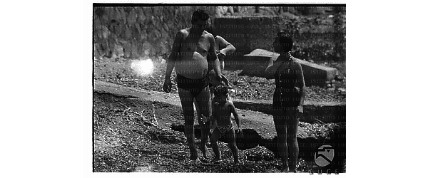 Un uomo ed una donna con due bambini ripresi in piedi sugli scogli di Santa Marinella - totale