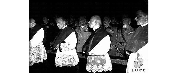 Ferrara De Bono, De Vecchi, Teruzzi, Bottai e gerarchi, ripresi in piedi in un interno, partecipano a una cerimonia religiosa