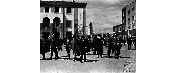 Latina Hans Frank, la moglie Brigitte, Marpicati e altre personalità camminano nei pressi del Comando dei Reali Carabinieri; sullo sfondo si scorge il Palazzo Comunale