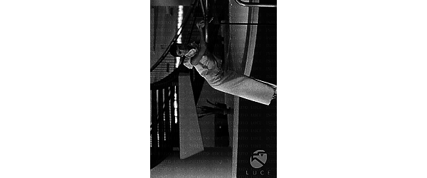 Barbara Steele in abito da sera, appoggiata a un corrimano sotto una scalinata circolare all'interno dell'Hotel Hilton; totale