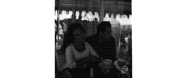 Elisabeth Taylor e Michael Todd ripresi seduti ad un tavolino di bar a  Roma - piano medio