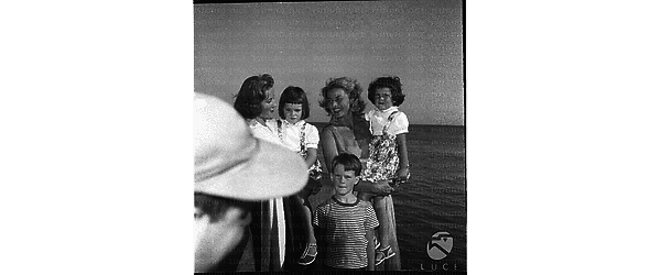 Ingrid Bergman e Friedel Pia Lindstrom, tenendo in braccio le piccole Isotta e Isabella Rossellini, posano per l'obiettivo insieme al piccolo Robertino sullo sfondo delle acque di S. Marinella. Piano americano