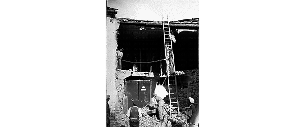Resti di un'abitazione, colpita dal terremoto del Vulture, con operai impegnati in lavori di ricostruzione