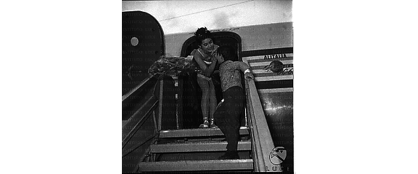 Vera Tschechowa ripresa in cima alla scaletta dell'aereo mentre accarezza un bambino - totale