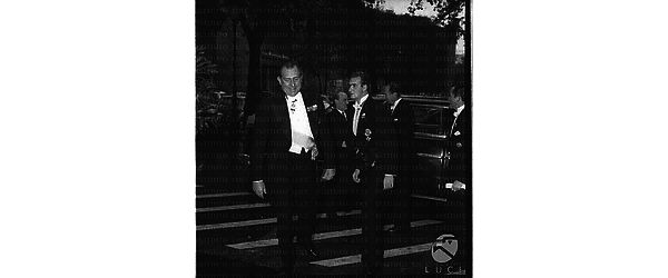 Don Juan  di Borbone conte di Barcellona ripreso elegantemente vestito mentre attraversa la strada sotto lo sguardo del figlio Juan Carlos - totale