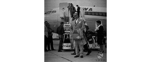 Il regista americano Raoul Walsh sulla pista dell'aeroporto di Ciampino, alle sue spalle un aereo della TWA - totale