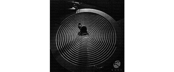 Barbara Steele in piedi su una struttura circolare a cerchi concentrici all'interno dell'Hotel Hilton; campo lungo, dall'alto