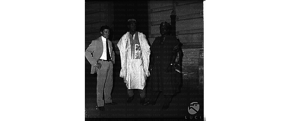 Due africani con abiti abiti tradizionali ed un uomo in una strada di Roma - totale