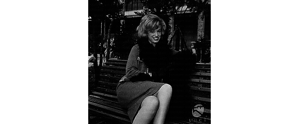 Margaret Lee seduta su una panchina in un giardinetto di periferia - piano americano